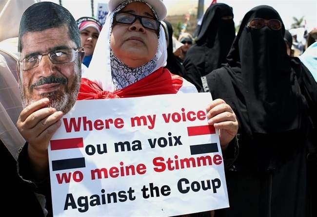 A supporter of ousted Egyptian President Mohammed Morsi holds a mask of Morsi and a banner as she attends a demonstration in front the National Council for Human Right building, in Cairo, Egypt, Sunday, July 21, 2013.
