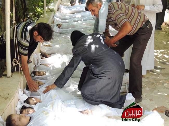A Syrian man helps a woman as she mourns over the dead bodies of children after an alleged poisonous gas attack fired by regime forces, according to activists in Arbeen town, Damascus, Syria, Wednesday, Aug. 21, 2013. (AP Photo/Local Committee of Arbeen)