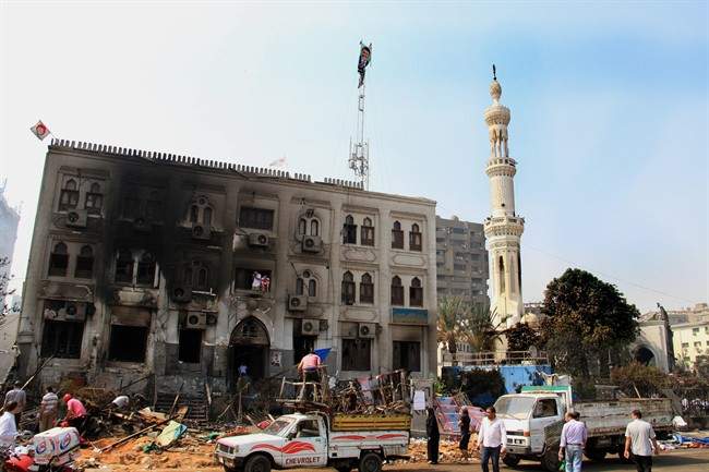 People inspect the burnt Rabaah al-Adawiya mosque with a poster of Egypt's ousted President Mohammed Morsi taped on its antenna in Cairo's Nasr City, Egypt, Thursday, Aug. 15, 2013.