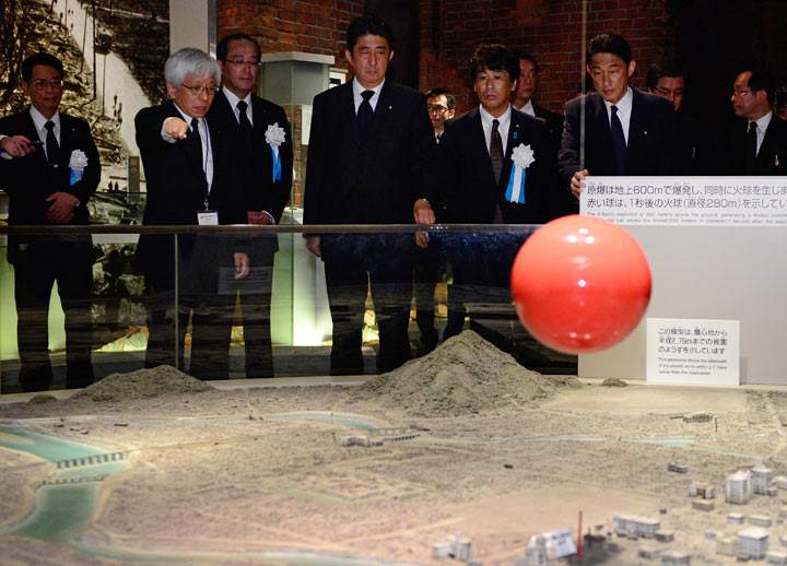 Japanese Prime Minister Shinzo Abe (C) listens to an explanation of the 1945 atomic bombing from Kenji Shiga (2nd L), director of the Hiroshima Peace Memorial Museum, at the museum in the Peace Memoral Park in Hiroshima on August 6, 2013 as ceremonies are held to mark the 68th anniversary of the US atomic bombing of the Japanese city.