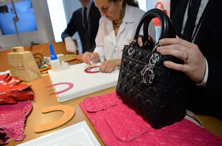 A craftswoman works on the handle of a bag at the accessories workshop of French luxury brand Dior in Paris on June 15, 2013. 