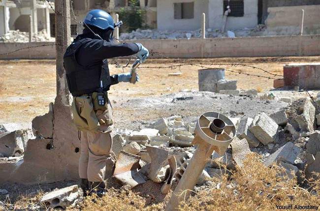 A member of a UN investigation team takes samples of sands near a part of a missile is likely to be one of the chemical rockets according to activists, in the Damascus countryside of Ain Terma, Syria. 