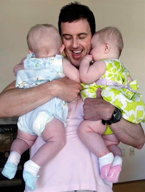 In this Tuesday, Aug. 20, 2013 photo, Trey Powell cuddles his six-month-old daughters Kylan, left, and Ashton in their home in Seattle. 