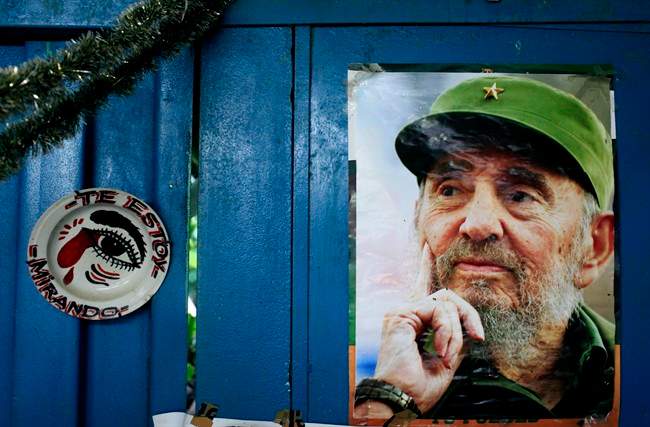 A poster of Cuba's Fidel Castro hangs on the wall of a food market in Havana next to a plate that reads in Spanish, "I'm looking at you," Tuesday, Aug. 13, 2013.