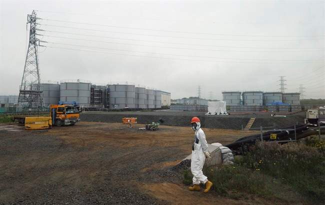 In this Wednesday, June 12, 2013 file photo, a construction worker walks beside the underground water tanks at the Fukushima Dai-ichi nuclear plant at Okuma in Fukushima prefecture, Japan.