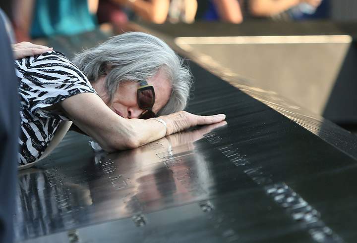 Mija Quigley, of Princeton Junction, N.J., embraces the name of her son, Patrick Quigley, during ceremonies marking the 12th anniversary of the 9/11 attacks on the World Trade Center in New York, Wednesday, Sept. 11, 2013. (Photo credit: AP Photo)