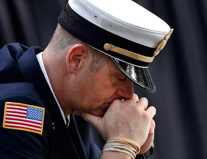 A firefighter pauses for a quiet moment as friends and relatives of the victims of 9/11 gather for a ceremony marking the 12th anniversary of the attacks at the National September 11 Memorial at the World Trade Center site, Wednesday, Sept. 11, 2013, in New York. (Photo credit: AP Photo)