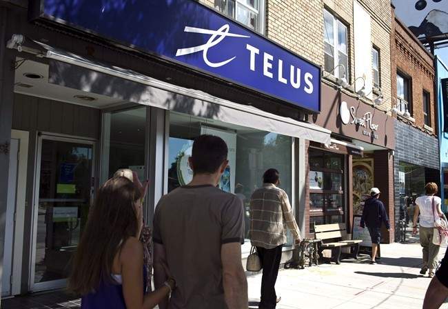 Pedestrians walk by a Telus store in Toronto, Thursday, August 15, 2013. 