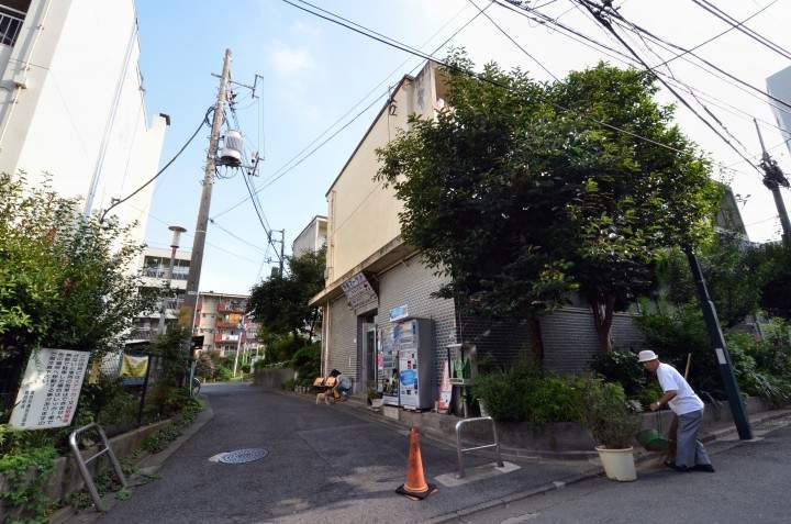 In this picture taken on September 14, 2013, 79-year-old resident Kohei Jinno (R) sweeps and cleans a road before his apartment complex near the rebuilt national stadium in Tokyo.  
