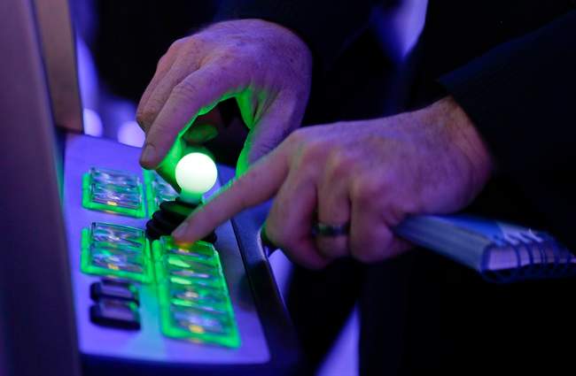 IGT account manager, George Kerrigan, demonstrates the use of a joystick and various buttons to play the Centipede video game slot machine at the Global Gaming Expo, Wednesday, Sept. 25, 2013, in Las Vegas. As the slot machine undergoes a generational shift, manufacturers are rolling out the first generation of joystick-controlled, penny arcade-themed gambling machines.