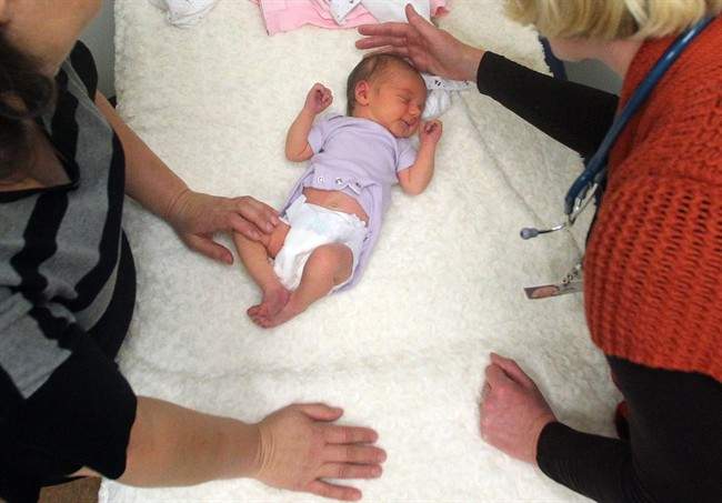 practitioner, right, examines a newborn girl accompanied by her mother in Portland, Ore.