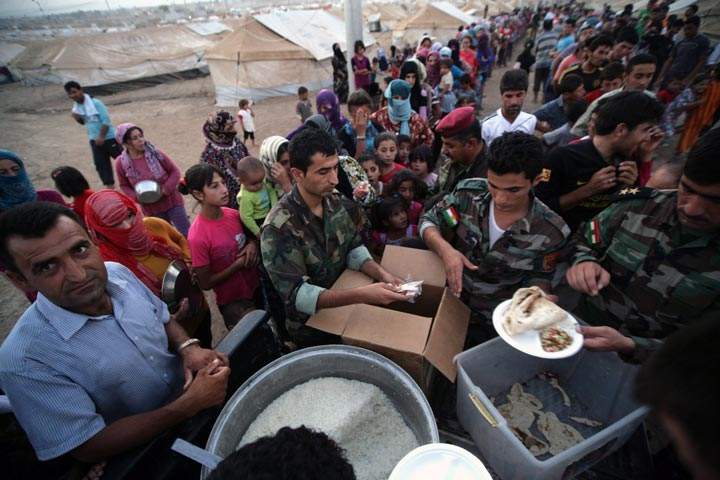 Syrian-Kurdish refugee families queue to get food at the Quru Gusik refugee camp, 20 kilometres east of Arbil, the capital of the autonomous Kurdish region of northern Iraq, on August 27, 2013.