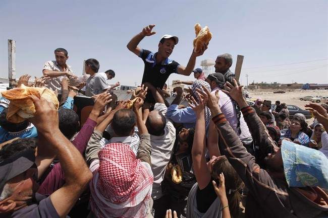 FILE - In this Aug. 20, 2013, file photo, Syrian refugees gather for food aid after cross into Iraq at the Peshkhabour border point in Dahuk, Iraq. 