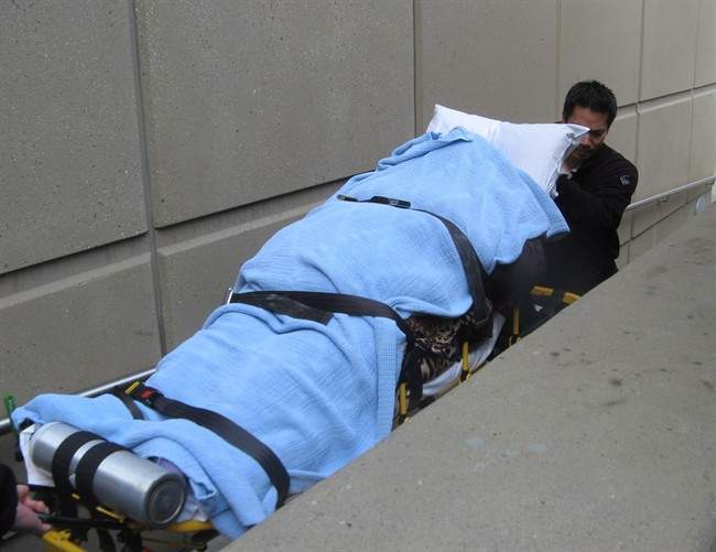 Health officials wheel Aset Magomadova into the Calgary Courts Centre on Tuesday, April 16, 2013. 