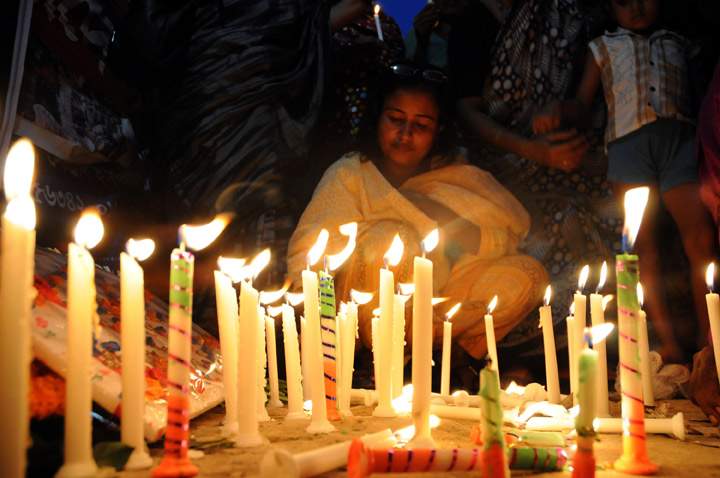 Bangladeshi garment workers and relatives of victims of the Rana Plaza building collapse hold candles during a memorial at the site of the Rana Plaza garment factory building collapse in Savar, on the outskirts of Dhaka on October 24, 2013, the six-month anniversary of the disaster.