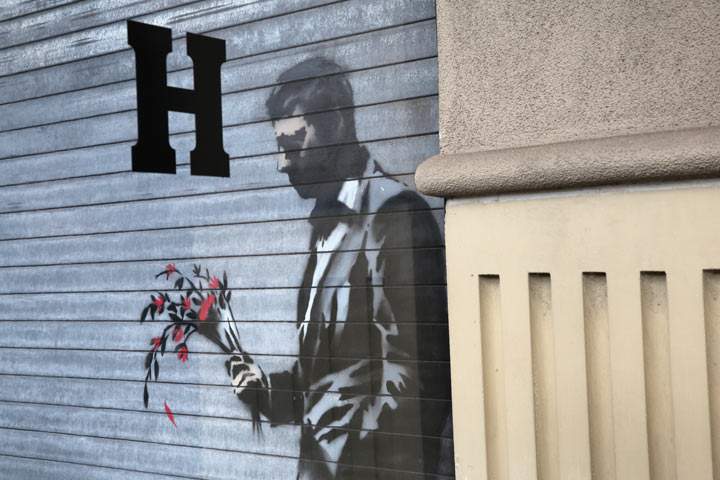 Graffiti by British street artist Banksy is seen on a roll-down security gate covering the main entrance to Larry Flint’s Hustler Club on October 24, 2013 in the Hell’s Kitchen neighborhood of New York City. On Banksy’s website a caption for the work reads, ‘Waiting in vain…at the door of the club.’
