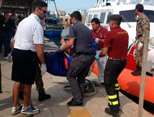 Firefighters unload the body of a drowned migrant from a Coast Guard boat in the port of Lampedusa, Sicily, Thursday, Oct. 3, 2013. Tens of people died when a ship carrying African migrants toward Italy caught fire and sank off the Sicilian island of Lampedusa, spilling hundreds of passengers into the sea, officials said Thursday. Many migrants have been rescued, but the boat is believed to have been carrying as many as 500 people. It is one of the deadliest migrant shipwrecks in recent times and the second one this week off Italy: On Monday, 13 men drowned while trying to reach southern Sicily when their ship ran aground just a few meters (yards) from shore at Scicli. 