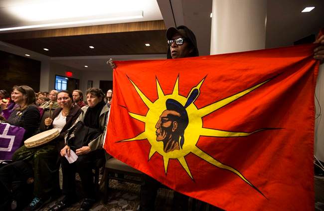 An indigenous man holds a flag during the National Energy Board public hearings on Enbridge Line 9 oil pipeline, in Toronto, Friday October 18, 2013. 