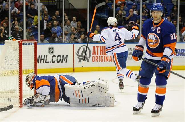 Edmonton Oilers' Taylor Hall (4) celebrates his second goal in the first period of an NHL hockey game as New York Islander' John Tavares (91) reacts and goalie Evgeni Nabokov (20) scrambles back up from the ice on Thursday, Oct. 17, 2013, in Uniondale, N.Y.