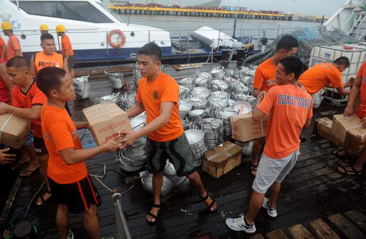 Philippine Coast Guard (PCG) personnel load frying fans and relief goods onto a PCG vessel at a port in Manila on October 16, 2013. (Photo credit: Getty Images)