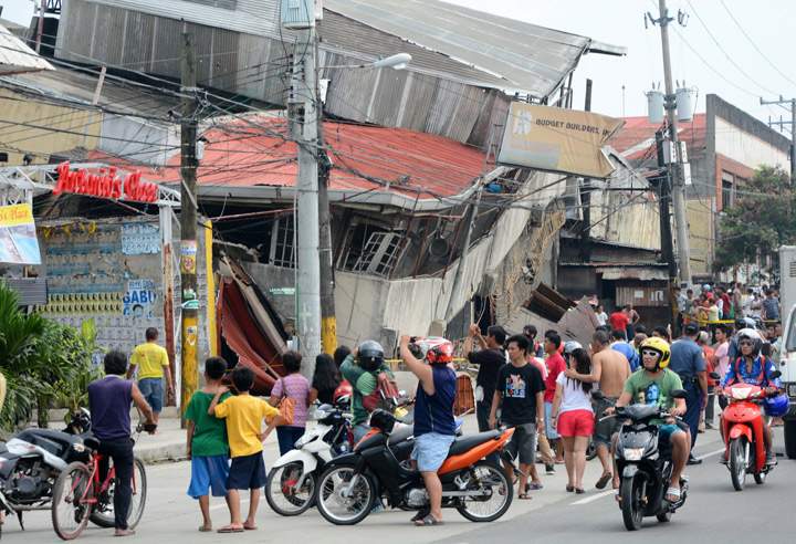People gather on the street next to damaged buildings in Cebu City, Philippines after a major 7.2 magnitude earthquake struck the region on October 15, 2013. (Photo credit: Getty Images)