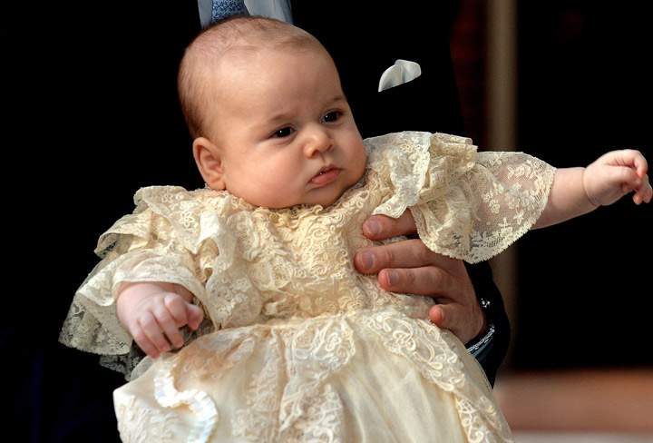 Britain’s Prince William, Duke of Cambridge holds his son, Prince George of Cambridge, as he arrives at Chapel Royal in St James’s Palace in central London for the christening of the three month-old baby on October 23, 2013.
