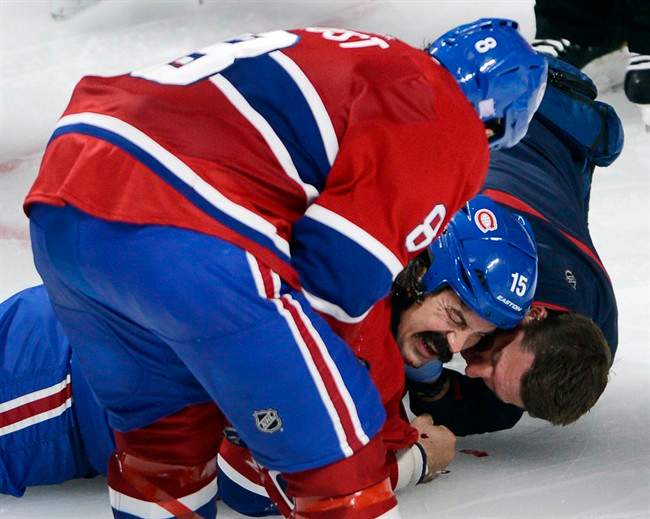 Montreal Canadiens winger George Parros (15) is treated by medical staff as teammate Brandon Prust looks on after he hit his head on the ice during a fight with Toronto Maple Leafs right wing Colton Orr during third period NHL action Tuesday, October 1, 2013 in Montreal. Parros was released from hospital on Wednesday, Oct. 2, 2013. 
