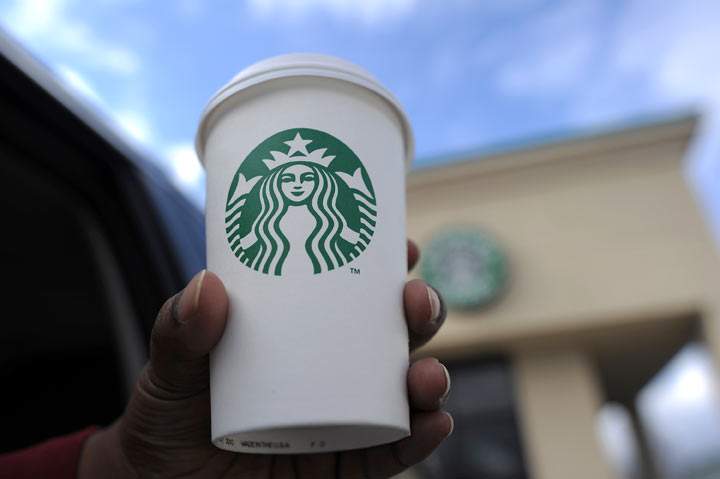 A woman holds up her cup in front of a Starbucks coffee shop in Silver Spring, Maryland, on March 28. 2013.