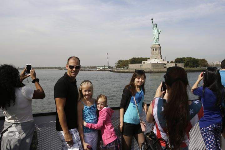 Tourists take photos of the Statue of Liberty while riding a tour boat in New York Harbor, Thursday, Oct. 3, 2013. The statue is administered by the National Park Service and is closed as a result of the government shutdown. 