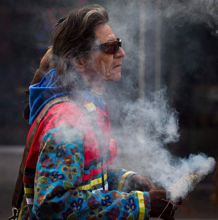 Robert Bonner, of the Nisichawayasihk Cree Nation in Nelson House, Man., is shrouded in smoke from burning sweetgrass while marching to a National Aboriginal Veterans Day ceremony at the Victory Square Cenotaph in Vancouver, on Friday November 8, 2013. (The Canadian Press/Darryl Dyckber)