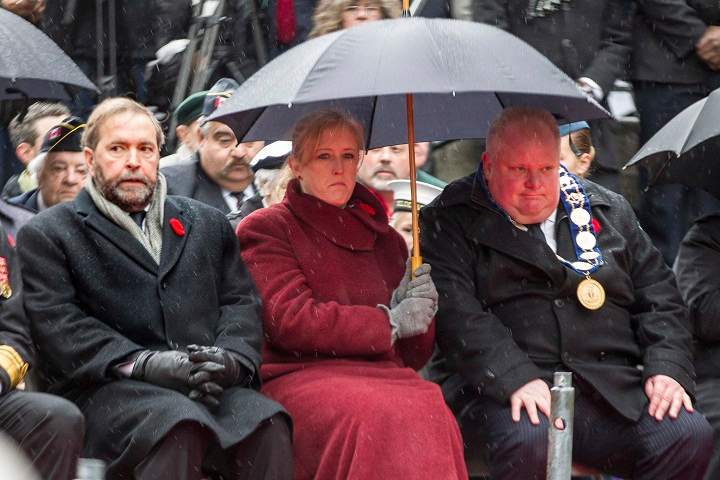 Toronto Mayor Rob Ford (right) sits with Federal Transport Minister Lisa Raitt (centre) and Leader of the Official Opposition Thomas Mulcair at the cenotaph during the Remembrance Day service in Toronto on Monday, November 11, 2013. (The Canadian Press/Chris Young)