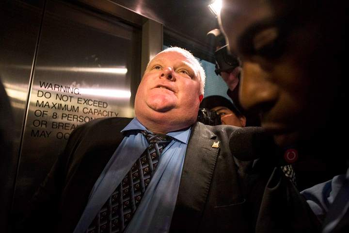 Toronto Mayor Rob Ford is caught in a crush of reporters as he waits for an elevator to return to the council chamber after councillors passed motions to limit his powers in Toronto on friday November 15, 2013.THE CANADIAN PRESS/Chris Young