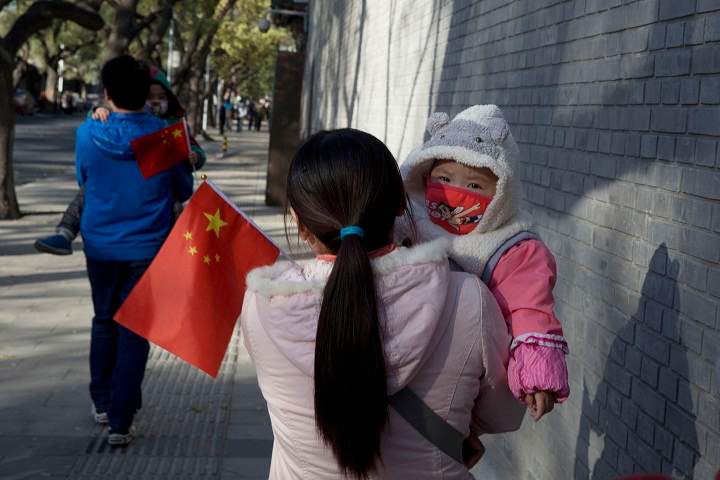 Visitors to the forbidden city carry children holding the Chinese national flags in Beijing, China, Saturday, Nov. 16, 2013. Some 15 million to 20 million Chinese parents will be allowed to have a second baby after the Chinese government announced Friday, Nov. 15, 2013 that couples where one partner has no siblings can have two children, in the first significant easing of the country’s strict one-child policy in nearly three decades.