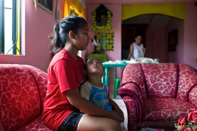 In this Nov. 21, 2013 photo, Shylyny Therese Negru, 15, holds her youngest brother, Rainier Aaron Dacuno, 3, as they sit in a relative's home in the town of Burauen, the Philippines. The children are among an unknown number in the eastern Philippines who lost their parents to the massive Nov. 8 storm. 