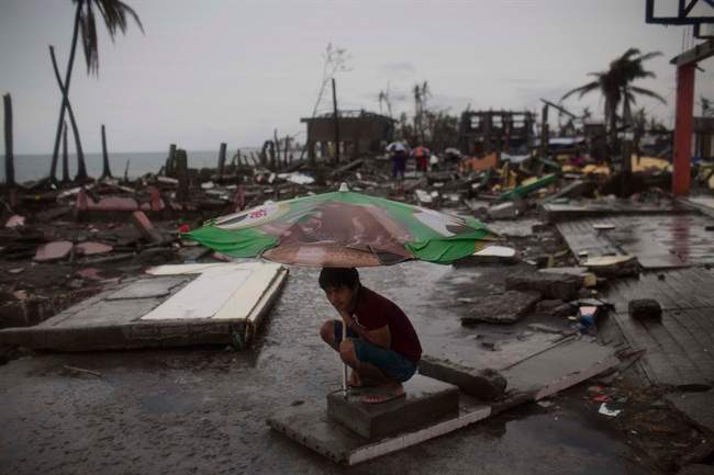 A Typhoon Haiyan survivor uses a market umbrella to protect himself from the rain in his destroyed neighborhood in Tacloban, Philippines, on Nov. 22.