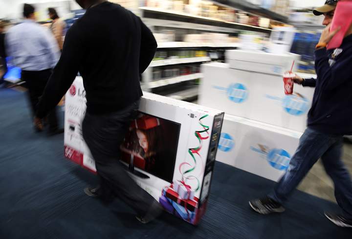 Black Friday shoppers carry away discounted items from at a Best Buy store which opened its doors at 6pm on Thanksgiving Day this year on November 29, 2013 in Naples, Florida. (Photo credit: Getty Images)