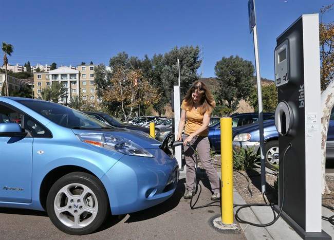 Angie Vorhies plugs in the charging cord to her Nissan Leaf electric vehicle at a mall Wednesday, Nov. 13, 2013, in San Diego.