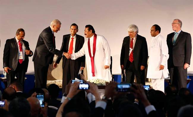 Sri Lankan President Mahinda Rajapaksa, center, shakes hands with Commonwealth Secretary-General Kamalesh Sharma as Sri Lankan Foreign Minister Gamini Lakshman Peiris, third left, and Commonwealth Business Forum (CBF) Chairman Mohan Kaul, third right, watch them during the inaugural session of the CBF in Colombo, Sri Lanka, Tuesday, Nov. 12, 2013. 