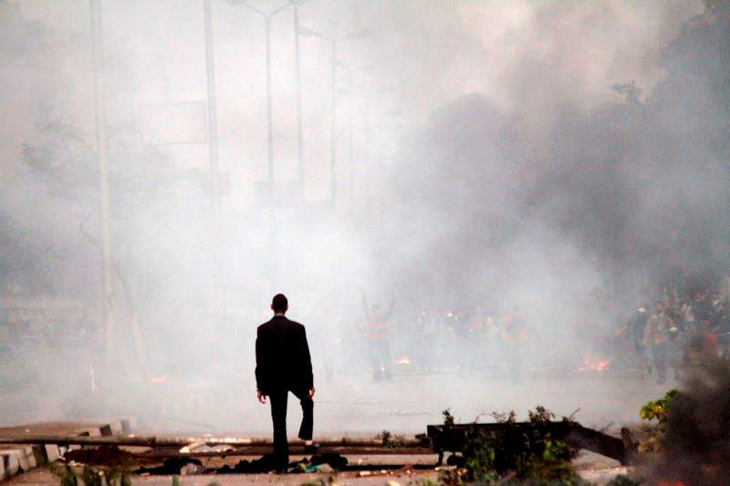 A man stands amid the smoke from tear gas fired by Egyptian riot police in Cairo, Egypt, Friday, Nov. 29, 2013, to disperse hundreds of Islamist demonstrators defying a new protest law.(AP Photo/Sabry Khaled, El Shorouk Newspaper)
