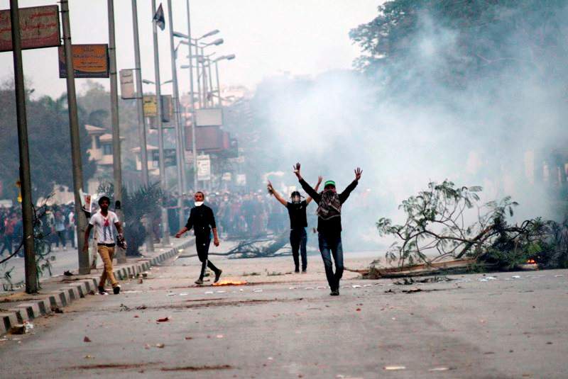 Protesters walk through a cloud of tear gas fired by Egyptian riot police in Cairo, Egypt, Friday, Nov. 29, 2013, to disperse hundreds of Islamist demonstrators defying a new protest law. (AP Photo/Sabry Khaled, El Shorouk Newspaper)