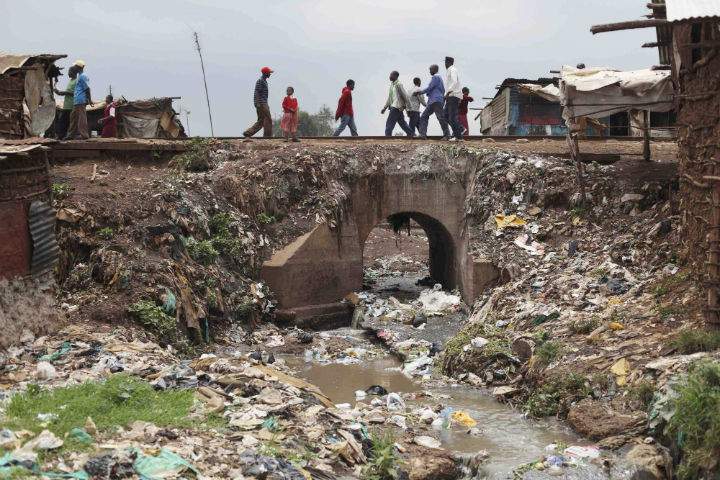 Slum dwellers cross a bridge over a stream of raw sewage, in the Kibera slum in Nairobi, Kenya, Wednesday May 27, 2009. 