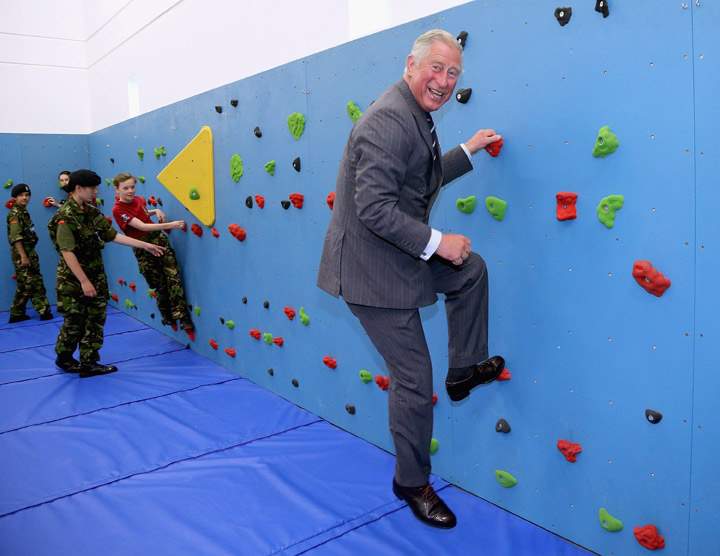 Prince Charles climbs on the new traversing wall in the new gym at Grainville Secondary School Prince Charles and Camilla Duchess of Cornwall Visit St Helier, Channel Islands on July 18, 2012. (Photo credit: AP Photo)