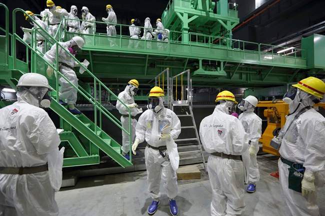 In this Nov. 7, 2013 file photo, members of the media and Tokyo Electric Power Co. employees walk down the steps of a fuel handling machine after looking at the spent fuel pool inside the building housing the Unit 4 reactor at the Fukushima Dai-ichi nuclear power plant.