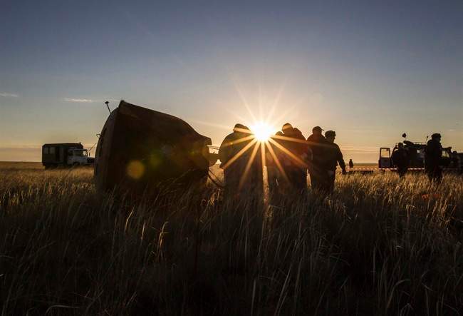 Search and rescue team members approach Soyuz TMA-09M capsule, left, carrying the International Space Station (ISS) crew, Fyodor Yurchikhin of Russia, Karen Nyberg of the United States and Luca Parmitano of Italy, that landed with a parachute in a remote area near the town of Zhezkazgan in central Kazakhstan Monday, Nov. 11, 2013. 