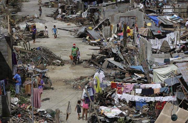 Survivors of Typhoon Haiyan walk amid ruins of their homes in Maraboth, Philippines, Thursday, Nov. 14, 2013. 