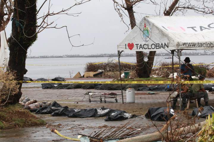 Members of the Philippine National Police talk amongst themselves next to body bags containing victims of Typhoon Haiyan on November 12, 2013 near Tacloban, Leyte, Philippines. (Photo credit: Getty Images)