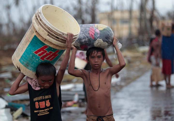 Survivors carry clothes along a road at typhoon-ravaged Tacloban city, Leyte province, central Philippines on Tuesday, Nov. 12, 2013. (Photo credit: AP Photo)