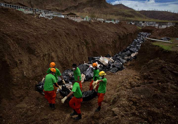 Rescue workers carry a body into a mass grave in the aftermath of Typhoon Haiyan November 16, 2013 outside of Tacloban, Philippines. Typhoon Haiyan has been described as one of the most powerful typhoons ever to hit land, leaving thousands dead and hundreds of thousands homeless. (Photo credit: Getty Images)