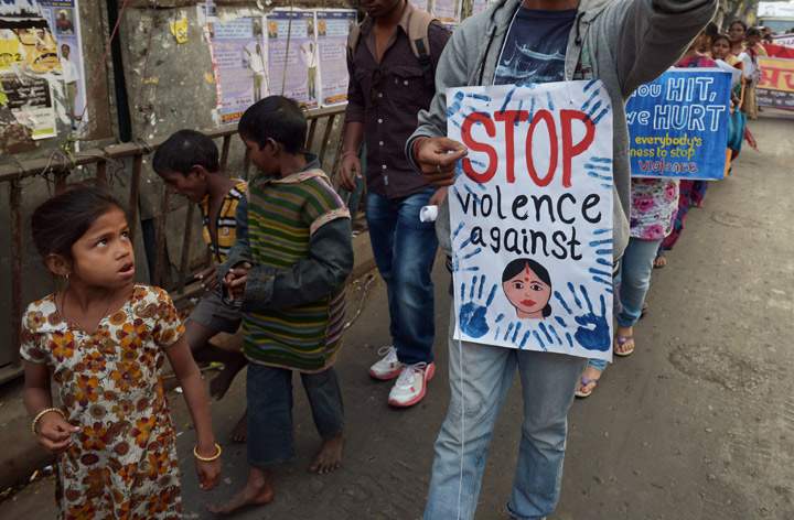 Street children look on as Indian social activists take part in a rally on the International Day for the Elimination of Violence against Women in Kolkata on November 25, 2013. (Photo credit: Getty Images)