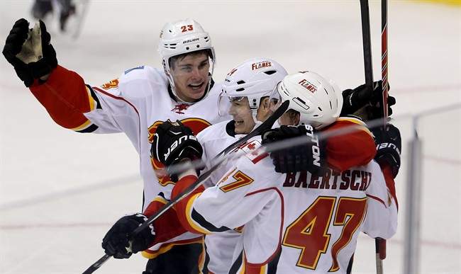 Calgary Flames' Sean Monahan (23), Jiri Hudler (24), and Sven Baertschi (47) celebrate a goal by Hudler against the Winnipeg Jets during third period NHL hockey action in Winnipeg Monday, November 18, 2013.